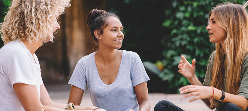 Three student sitting outside talking